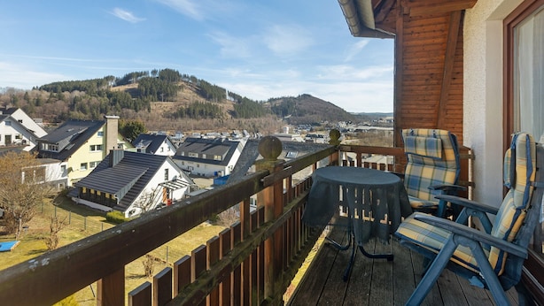 En balkon med udsigt over et boligområde, et bord og to stole.