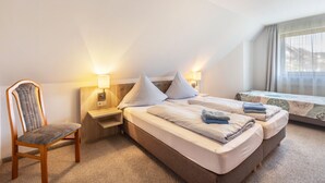 Une chambre d’hôtel avec un lit, une chaise, une table de chevet et une fenêtre avec des rideaux.