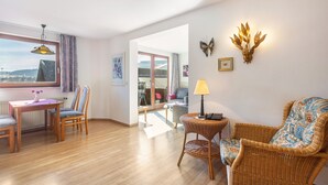 Une pièce comprenant une table à manger, des chaises, un canapé en osier, une lampe et des éléments décoratifs sur les murs.