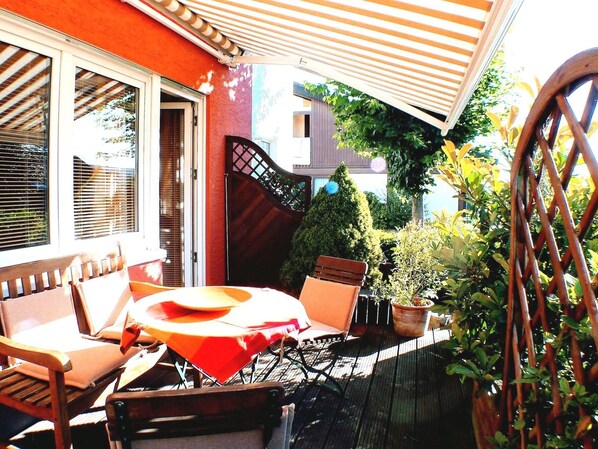 An outdoor patio with a round table, chairs, and a striped awning.