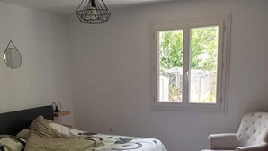 Ein Schlafzimmer mit Bett, Stuhl, Fenster und einer Pendelleuchte.