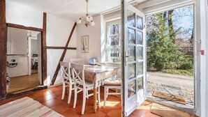 A dining area with a table and chairs, a chandelier, and a view through a glass door.