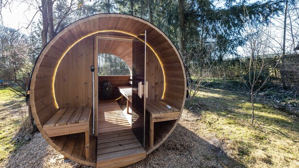 A wooden cabin with a circular design, a bench, and a door.