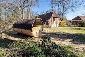 En trätrumma i en naturlig miljö, med en traditionell byggnad i bakgrunden.
