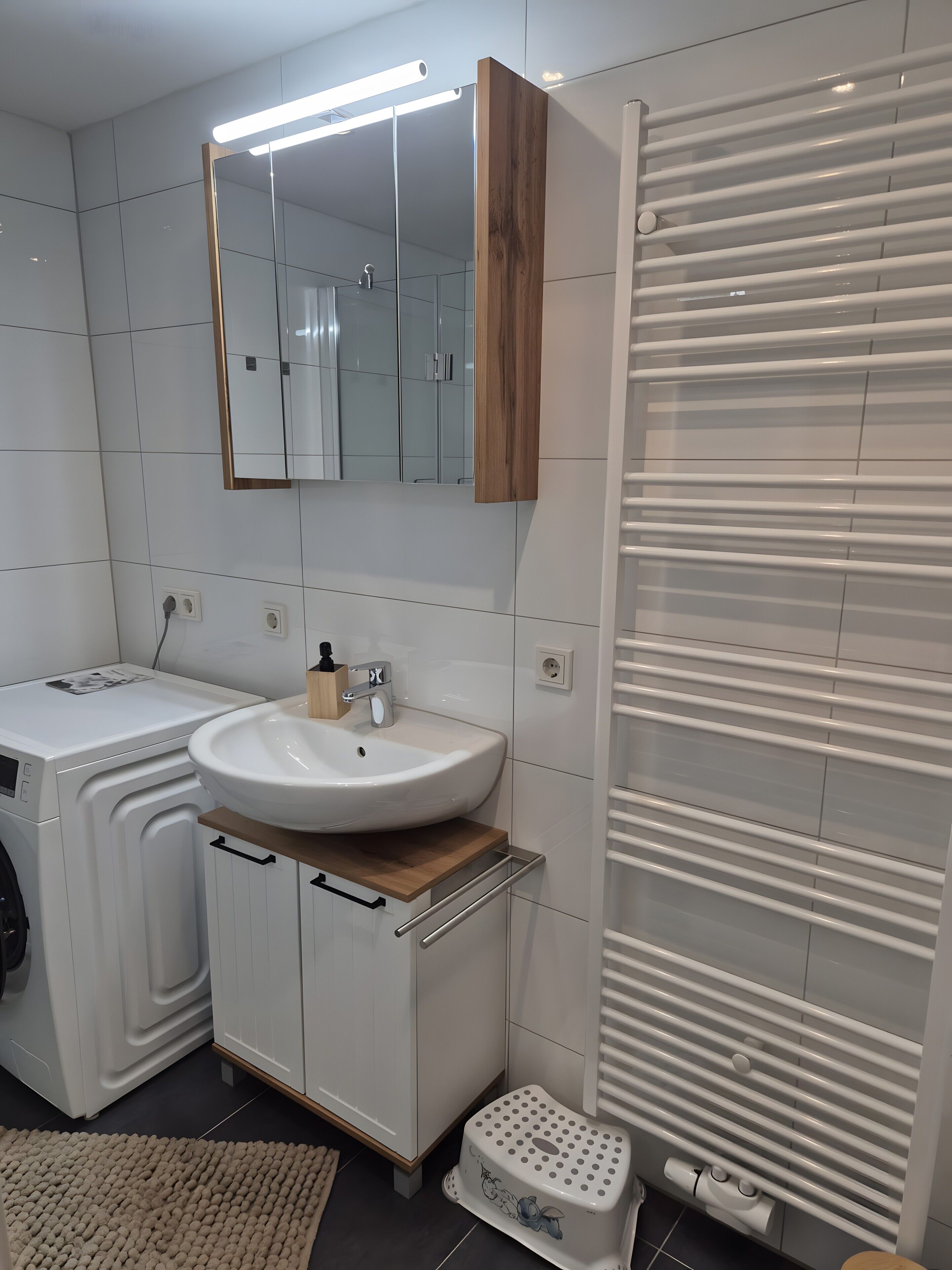 Ein modernes Badezimmer mit Waschbecken, Spiegel und integriertem Heizlüfter.