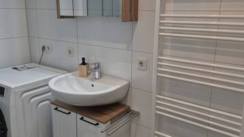 Ein modernes Badezimmer mit Waschbecken, Spiegel und integriertem Heizlüfter.