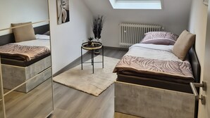 Un dormitorio con tragaluz, una cama, una mesita de noche con lámpara y un radiador.