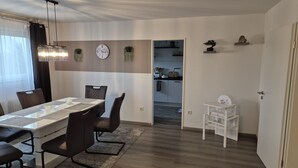 Un comedor moderno con una mesa larga, sillas y una lámpara de araña.