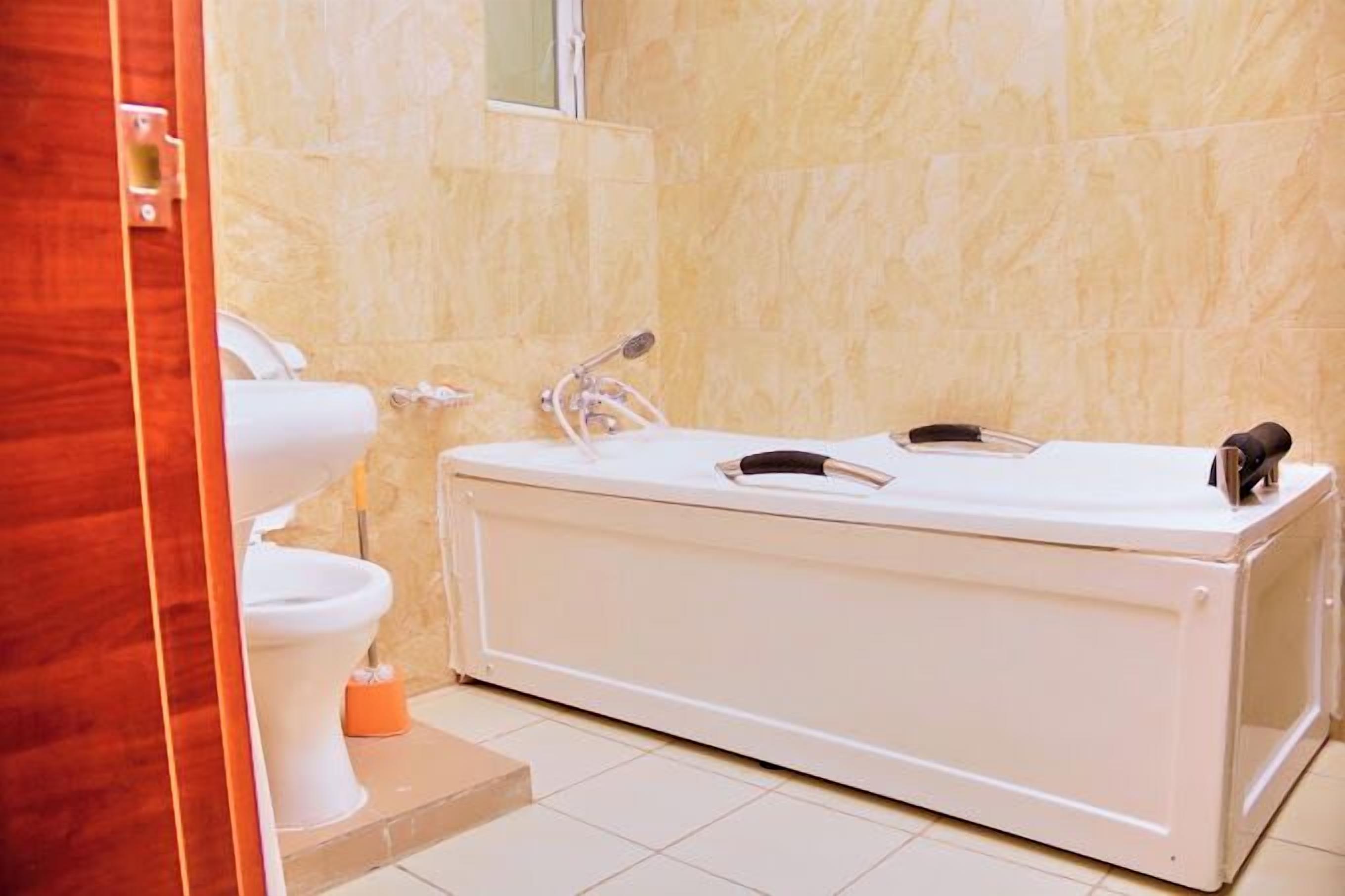 Ein Badezimmer mit Toilette, Waschbecken und einer tragbaren Badewanne.