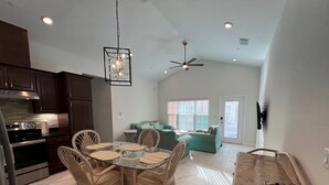 A spacious kitchen with dark wooden cabinets, a stainless steel stove, and a glass dining table with wicker chairs.