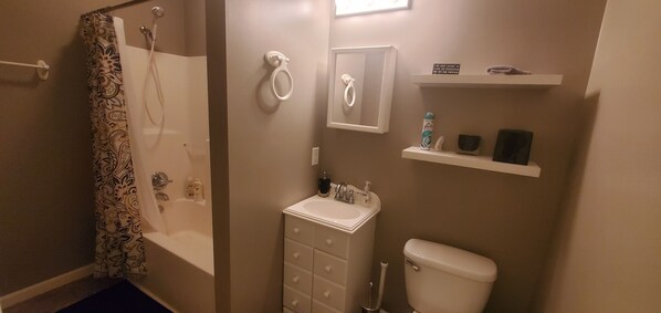 Baño con ducha, inodoro, lavabo y toallero.