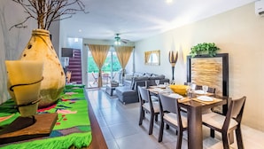 A modern living room with a sofa, dining table, and chairs. There is a large vase and a decorative wall piece. - Luxury Penthouse with 2 BR - Meridian (Playa del Carmen)