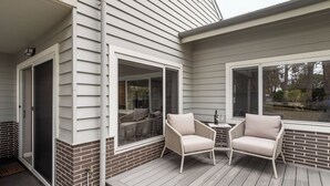 A covered patio with two chairs and a table, a sliding glass door, and a brick base. - Station Stays | Margaret River NEW (Margaret River)