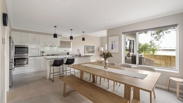 Una cocina moderna con armarios blancos, una isla central e iluminación colgante.