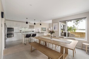 Una cocina moderna con armarios blancos, una isla central e iluminación colgante.