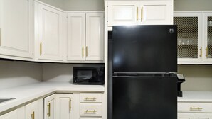 A kitchen with white cabinets, a black refrigerator, and a microwave. - Nicely Located 2-bedroom duplex apartment newly updated in Herington. (Herington)