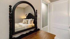 A bedroom with a wooden bed frame, a large mirror, and a white door. - Nicely Located 2-bedroom duplex apartment newly updated in Herington. (Herington)
