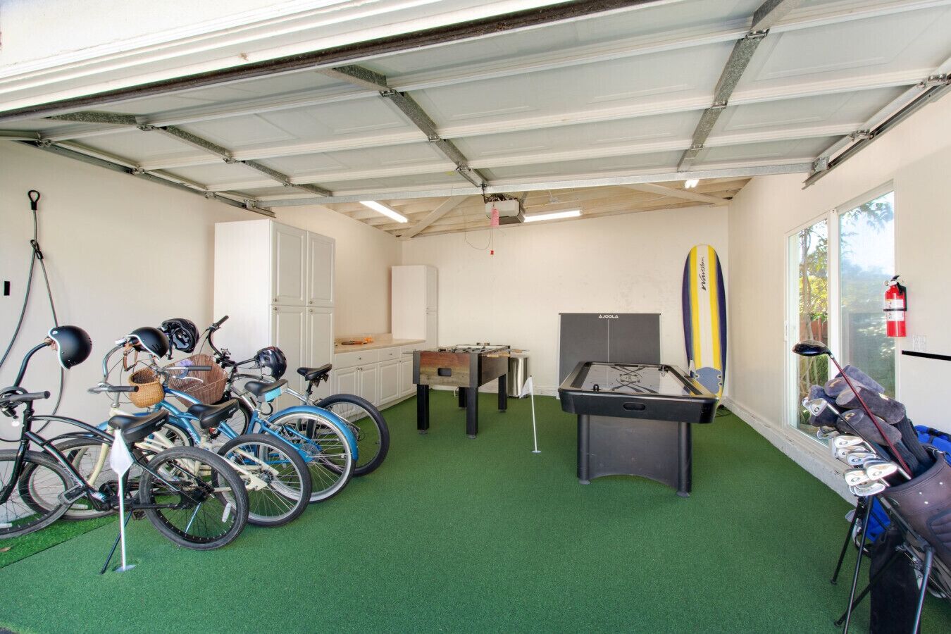 Une pièce avec des vélos, un baby-foot et une planche de surf.