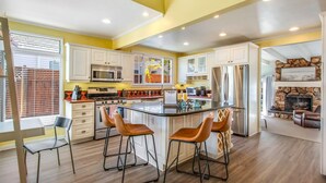 A modern kitchen with white cabinets, stainless steel appliances, and a central island with bar stools.