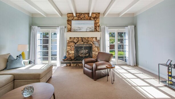 A living room with a stone fireplace, a leather armchair, and a sofa.