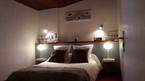 Une chambre à coucher avec un lit, deux tables de chevet et deux lampes fixées au mur.