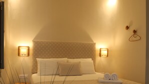 Een keurig opgemaakte slaapkamer met een bed, nachtlampjes en een bloevas.