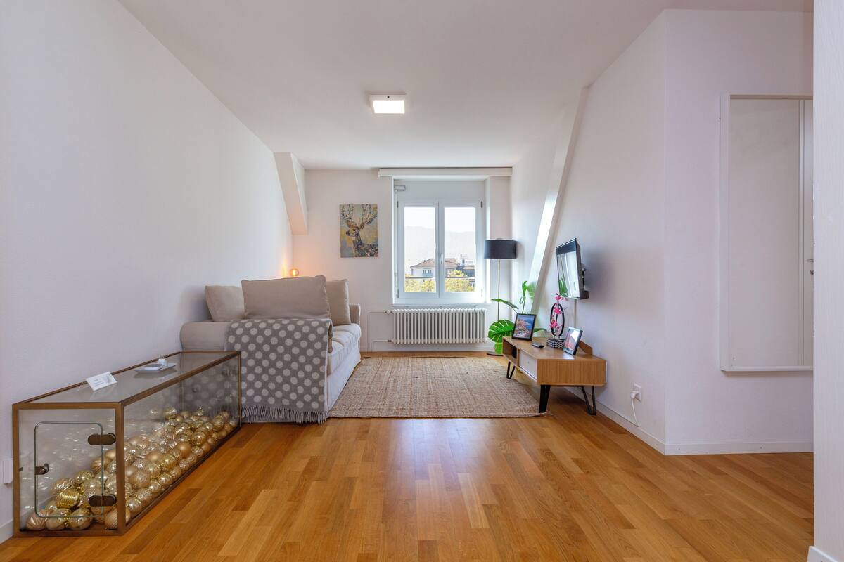 Ein modernes Wohnzimmer mit einem Glastisch, einer Couch, einem Holzbüro und einer Heizung.