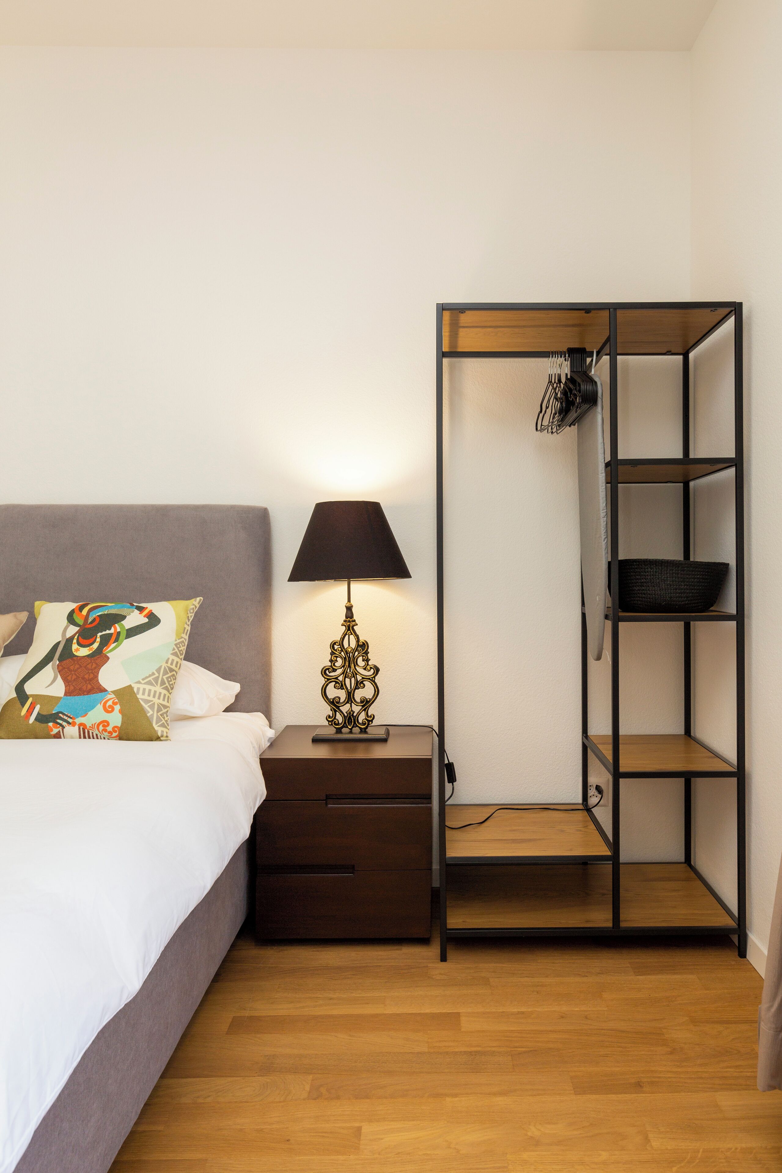 Een slaapkamer met een bed, een bedlamp, een kledingkast en een klein tafeltje.