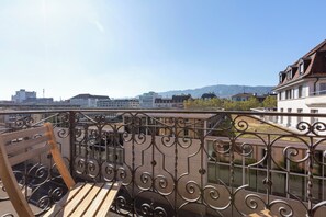 Relax on the balcony overlooking the scenic river with a view of the modern buildings in the distance.