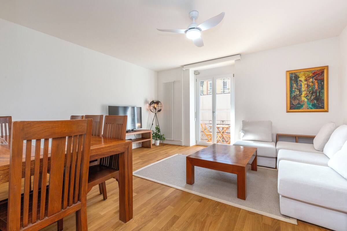 Ein modernes Wohnzimmer mit einem Holzesstisch, einem weißen Sofa und einem Deckenventilator.