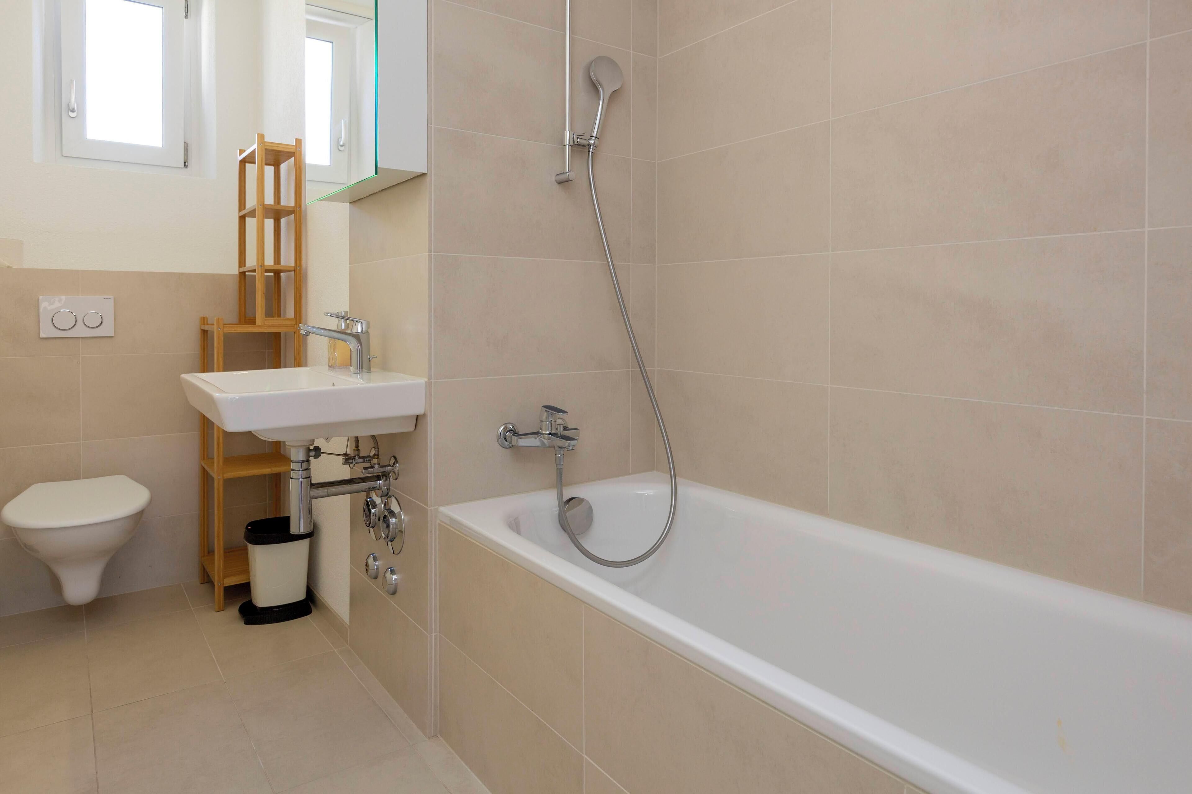 Un baño con bañera, lavamanos, inodoro y espejo.