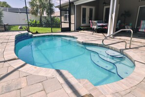 Relax by the pool surrounded by a deck with a curved edge and a metal ladder leading into the water.