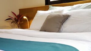 A neatly made bed with white linens and a teal throw blanket.