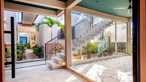 A spacious indoor area with a staircase, potted plants, and a view of the outside.