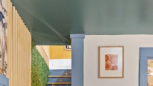 A cozy living room with a green sofa, a small white table, and a staircase with star patterns.