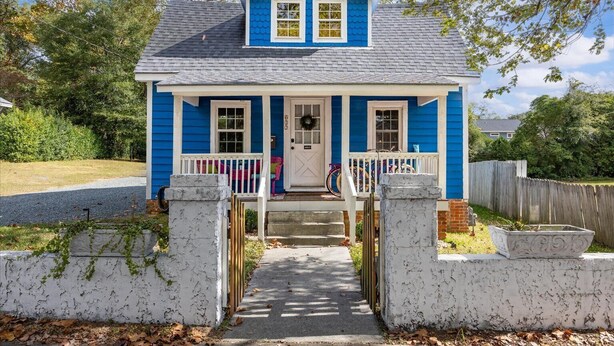 A two-story house with a blue exterior, white trim, and a front porch with a white railing.