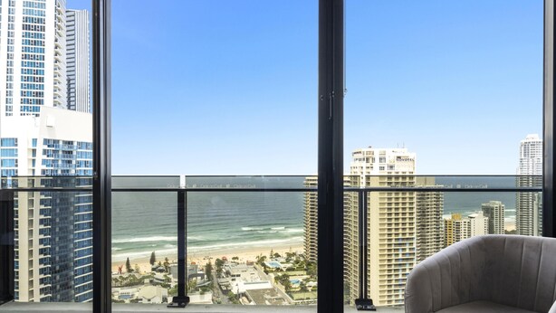 A high-rise hotel room with a large window overlooking a beach and ocean. - 1 Bedroom + Study Ocean View Apartment — Q Stay (COC 1313 - 2N - NB) (Surfers Paradise)