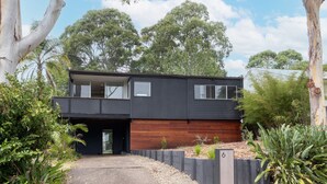 A modern two-story house with a flat roof, large windows, and a wooden deck. - Lightly Salted in Mollymook (Mollymook Beach)