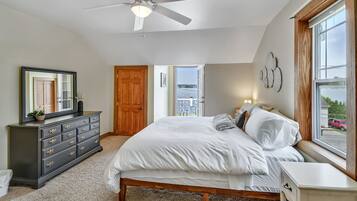 Quarto com cama, cômoda, ventilador de teto e janela com vista para o exterior.
