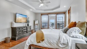 A bedroom with a bed, a dresser, a TV, and a window with a view.