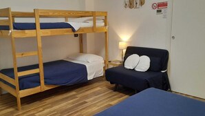 Kerrossänky, jossa on työpöytä ja tuoli, lamppu ja ovi, jossa on kyltti.