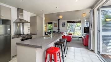 A modern kitchen with a central island, stainless steel appliances, and a dining area with red bar stools.