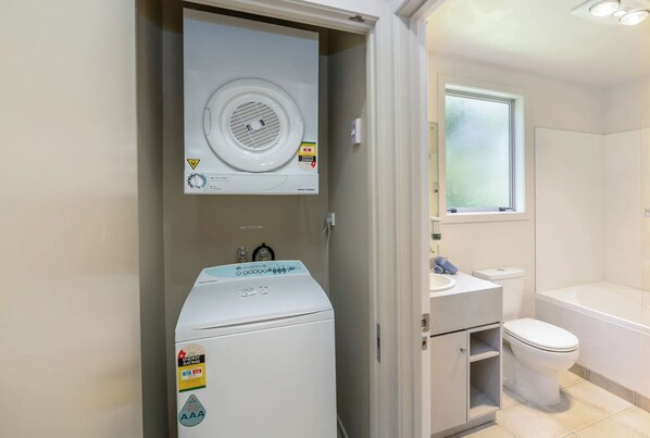 A compact bathroom with a washing machine, a toilet, and a sink. - Apartment Sauvignon, Martinborough (Martinborough)