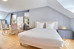 Un dormitorio moderno con una cama grande, dos mesitas de noche, una silla y un espejo.