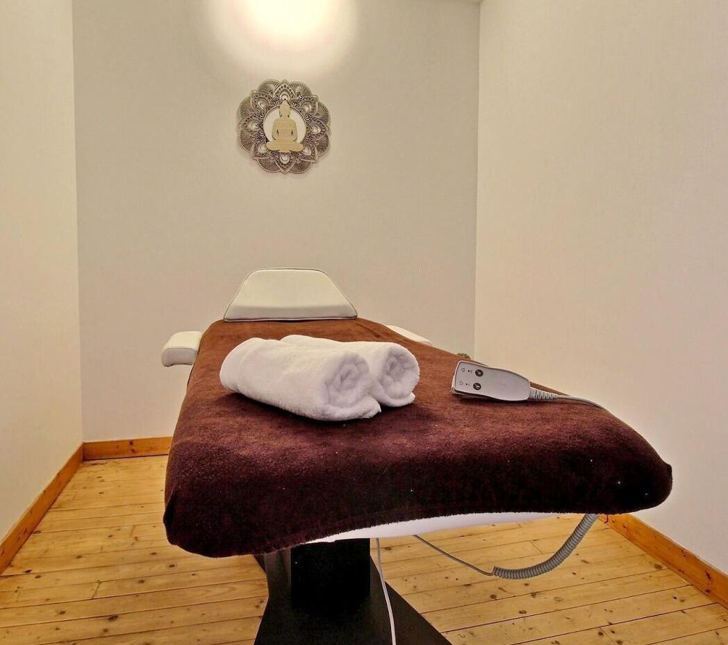 A massage table with a white towel and a remote control.