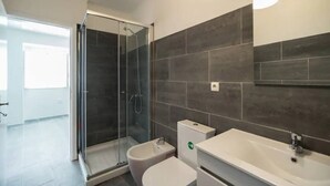A modern bathroom with a glass-enclosed shower, a bidet, a toilet, and a sink. - Charming Alfama Flat (Lisboa)