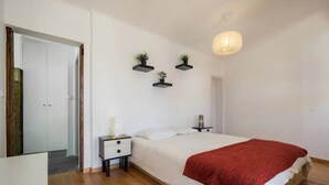 A bedroom with a bed, bedside tables, a wardrobe, and a hanging light fixture. - Charming Alfama Flat (Lisboa)