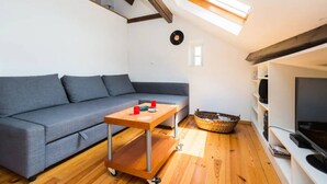 Ein modernes Wohnzimmer mit grauem Sofa, einem Holztisch, einem Fernsehschrank und einem Oberlicht.