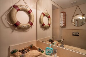 A bathroom with two life rings on the wall, a mirror, and a sink with toiletries. - Mangroovy Seafront condo - Great Kite Surfing - Luxury El Gouna   (Red Sea Governorate)