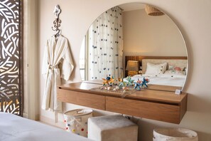 A hotel room with a wooden vanity, a large mirror, a bed with white bedding, and a decorative starfish arrangement on the vanity. - Mangroovy Seafront condo - Great Kite Surfing - Luxury El Gouna   (Red Sea Governorate)